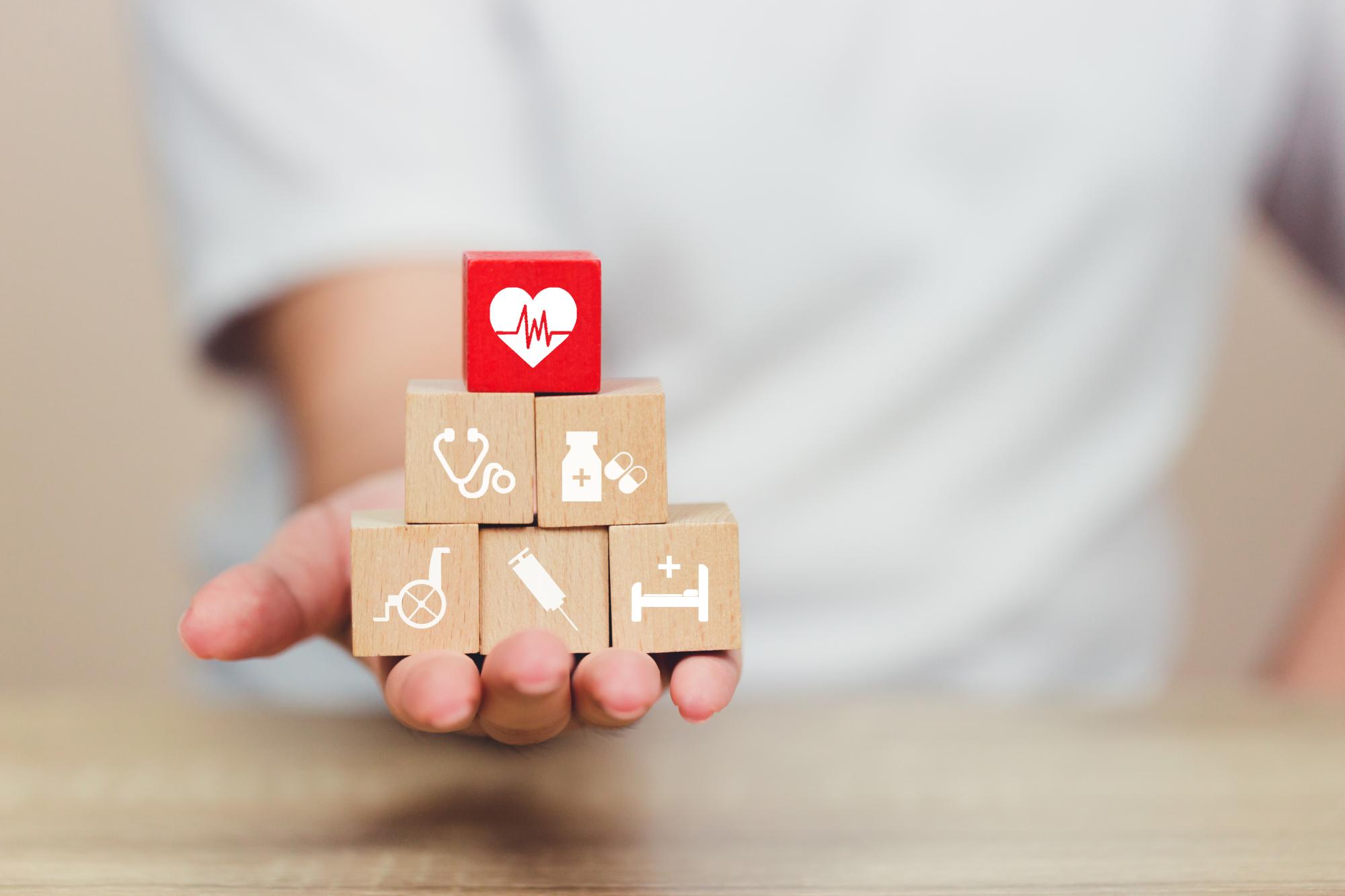 Hand extended holding blocks with images representing health, life, commercial, and home insurance.