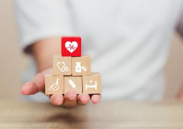 Hand extended holding blocks with images representing health, life, commercial, and home insurance.